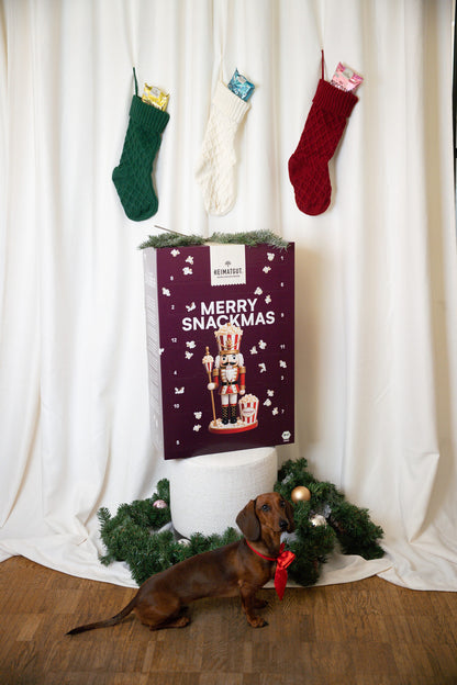 Heimatgut Adventskalender 2026 vor Weihnachtsstrümpfen mit Dackel
